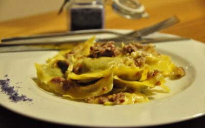 Ravioloni al radicchio con salsa alla salsiccia, crema di latte, granella di nocciole tostate e sale al crauto rosso dello chef Enrico Fiorentini.